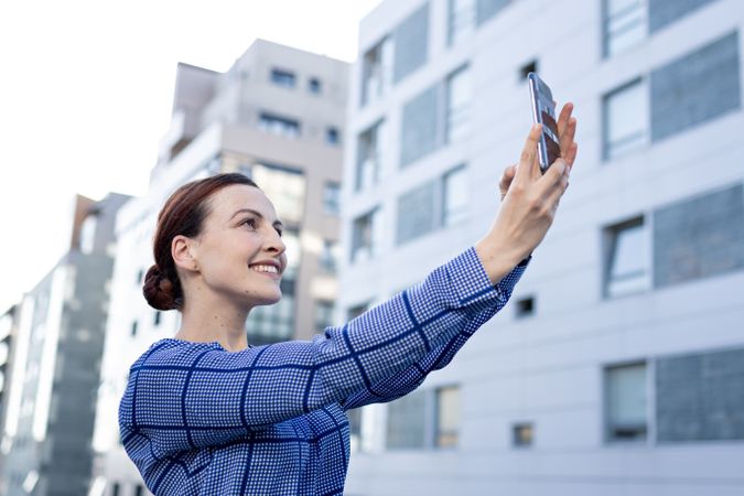 Smiling businesswoman taking selfie on street