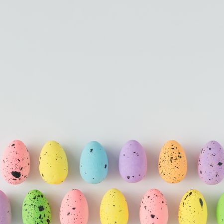 Rows of pastel Easter eggs on light background