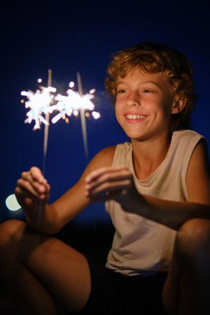 Positive boy celebrating holiday with sparklers