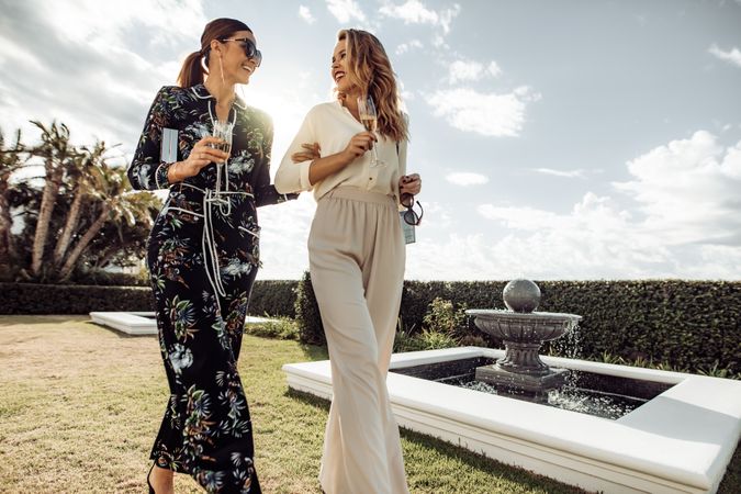 Stylish women friends with wine walking outdoors