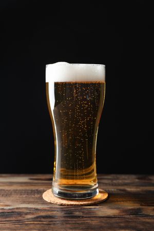 Mug with beer on wooden table, space for text