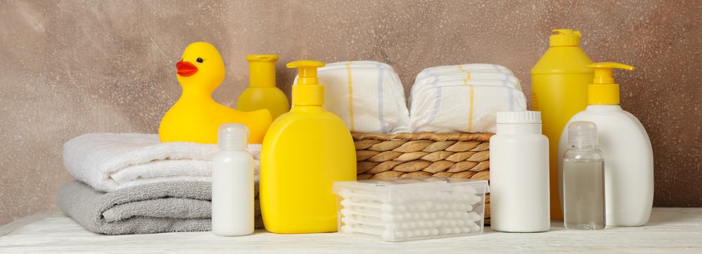 Baby hygiene accessories on wooden table against brown background