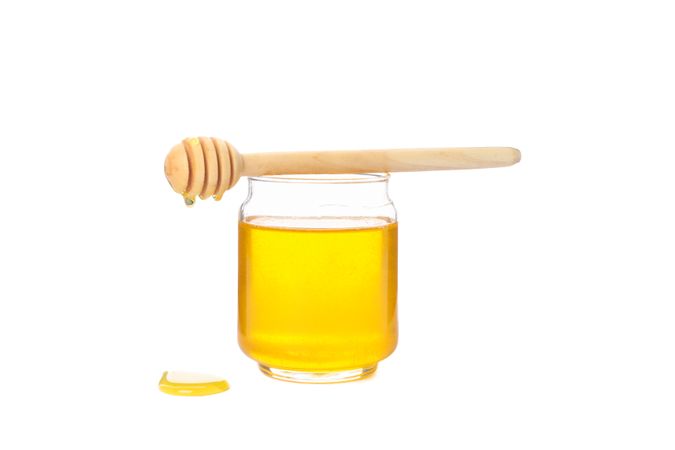 Dipper and glass jar with honey isolated on neutral background