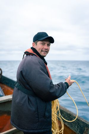 Patient lobster fisherman holding a rope on a boat