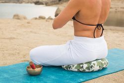 Woman practicing yoga outdoors near water