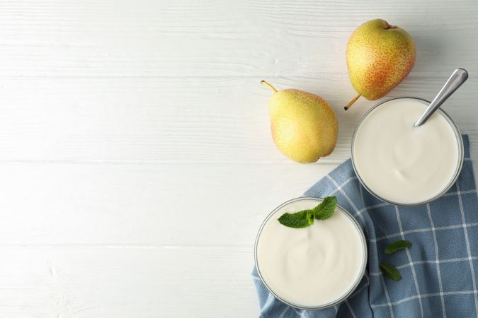 Cream yogurt, pears, towel and mint on wooden background, top view