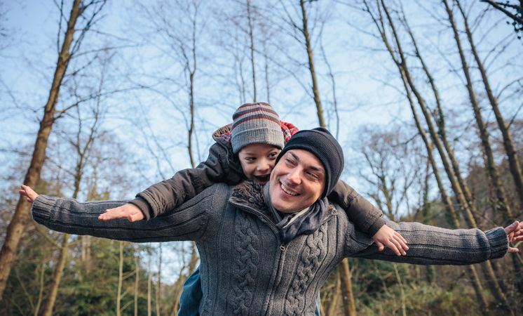 Father giving son ride on his shoulders in forest