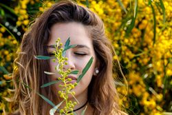 Young woman smelling flower from garden bush