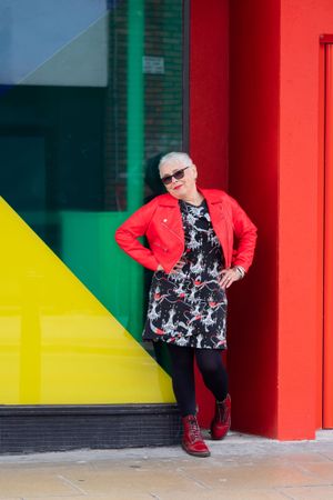 Grey haired woman in red leather jacket with hands on hip