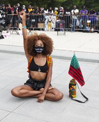 Woman sitting with raised fist at Black Lives Matter event, Washington, DC