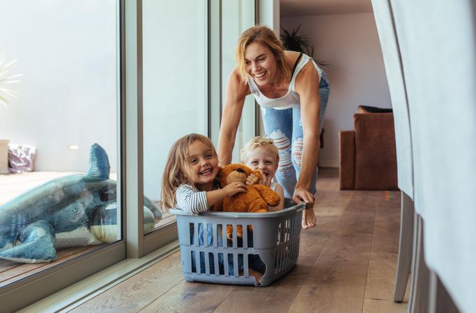 Happy young mother pushing children sitting in laundry basket