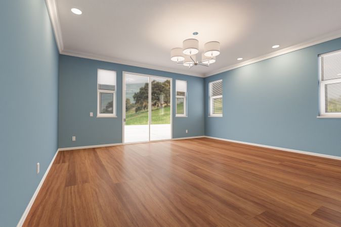 Newly Remodeled Room of House with Finished Wood Floors, Moulding, Blue Paint and Ceiling Lights.