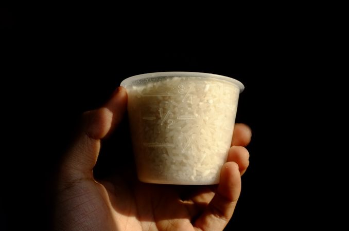 Person holding cup of rice
