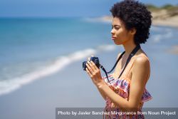 Woman with camera at the coast of beautiful beach 48RxX0