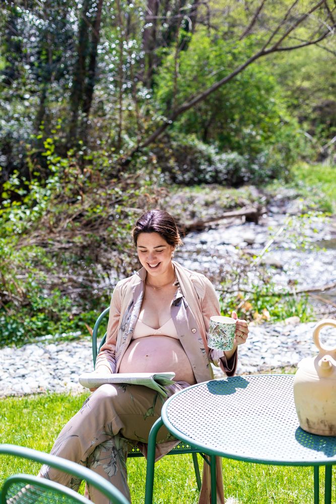 Smiling pregnant young woman reading newspaper outside