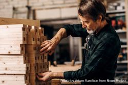 Mature man measuring stack of wooden planks in shop 5noVA4
