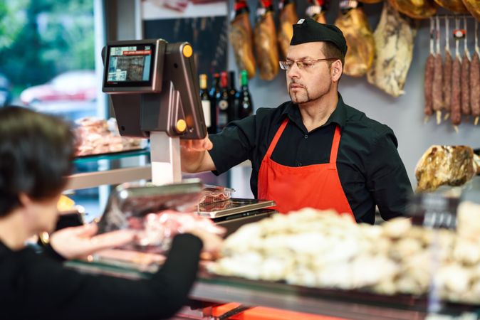 Man in butcher shop serving a customer