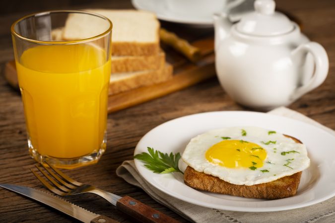 Breakfast with juice, coffee and toast with fried egg.