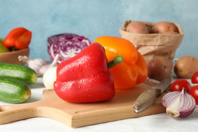 Vegetables, board and knife on wooden background, close up