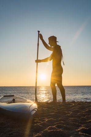 Man practicing paddle surfing with neoprene in a sunrise