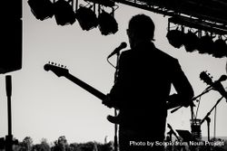 Back view of man singing and playing guitar on stage in grayscale 41Azl4