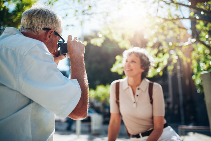 Older man taking vacation photographs of his wife