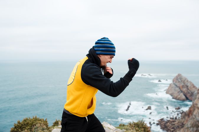 Kickboxer training on cliff near sea