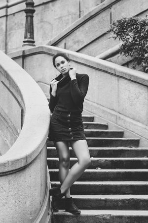 B&W portrait of calm woman in sweater outside standing on stairs