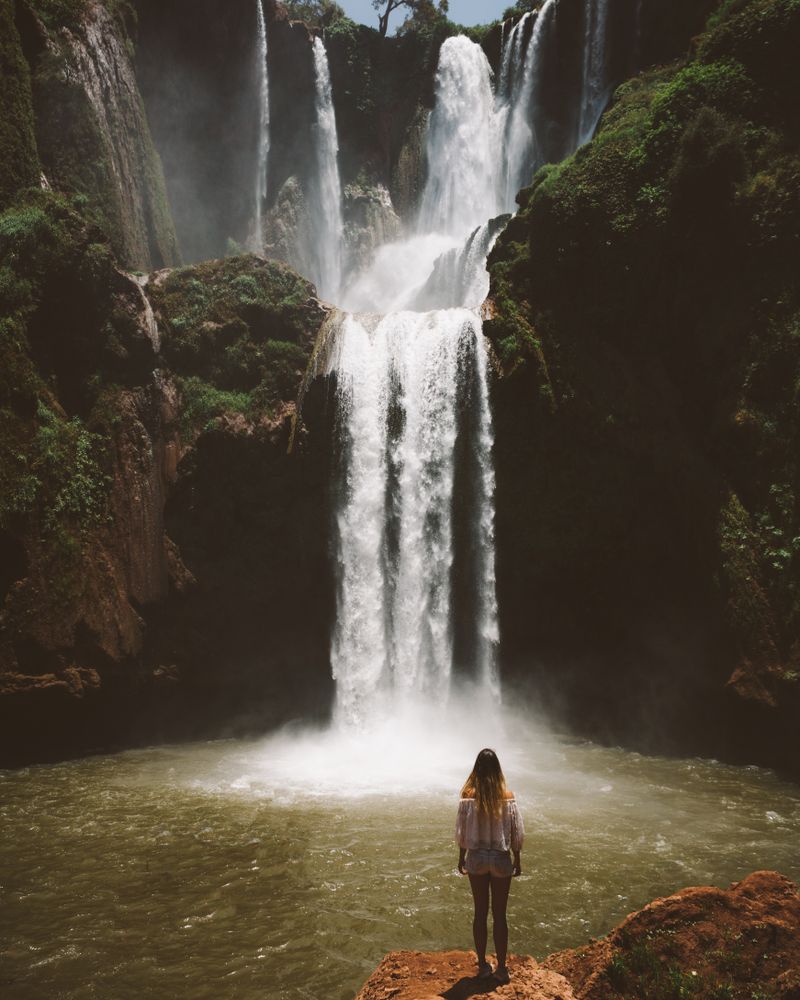 Woman in valley with amazing waterfall