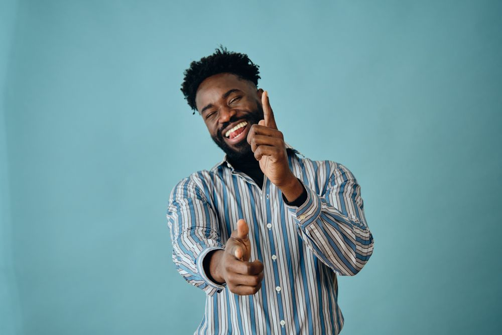 Joking Black man in striped shirt pointing at the camera