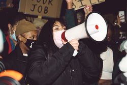 London, England, United Kingdom - March 16, 2021: Woman in face mask speaking into loudspeaker