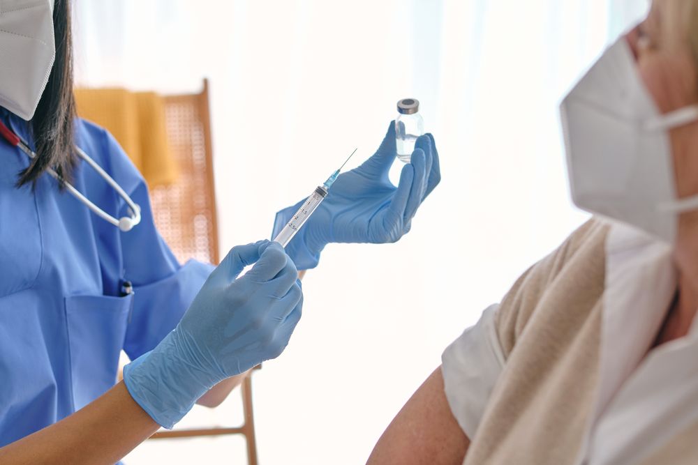 Crop physician with syringe and vaccine against female patient i