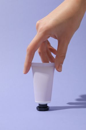 A jar of hand cream on a light, purple background.