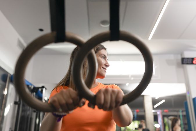 Portrait of a female trainee resting her hands on the rings at the gym