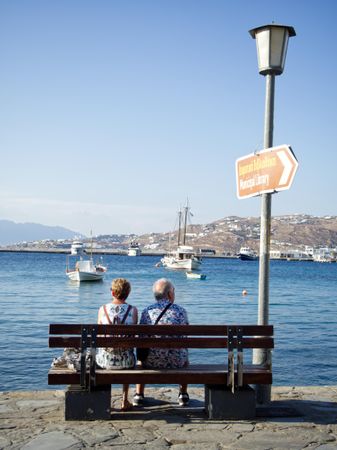 Older couple sitting on a bench near the water