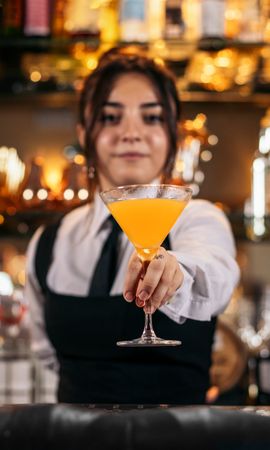 Young female bartender offering a drink