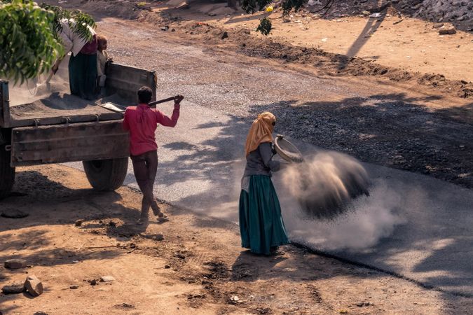 Laborers building an asphalt road in a village in India