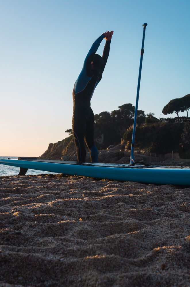 Man practicing paddle surfing with neoprene in a sunrise