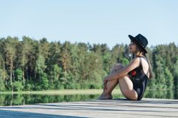 Young female sitting on pier on nature