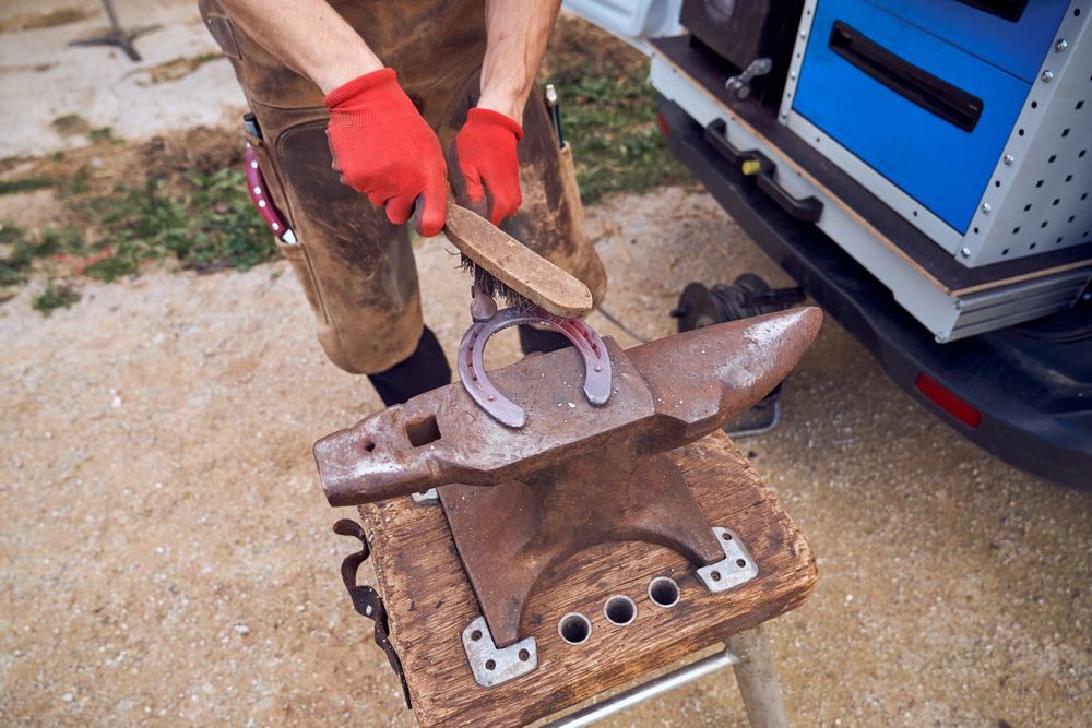 Blacksmith working on the anvil changing the horseshoe to a paw with tools