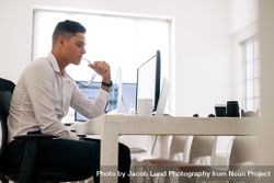 Man holding eyeglasses working on computer in office with a coffee cup on the table bxnKy5