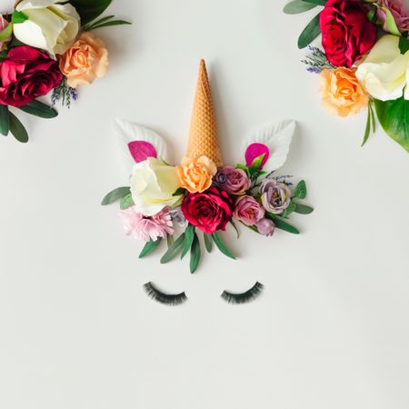 Unicorn head with colorful flowers, leaves and ice cream cone on light  background