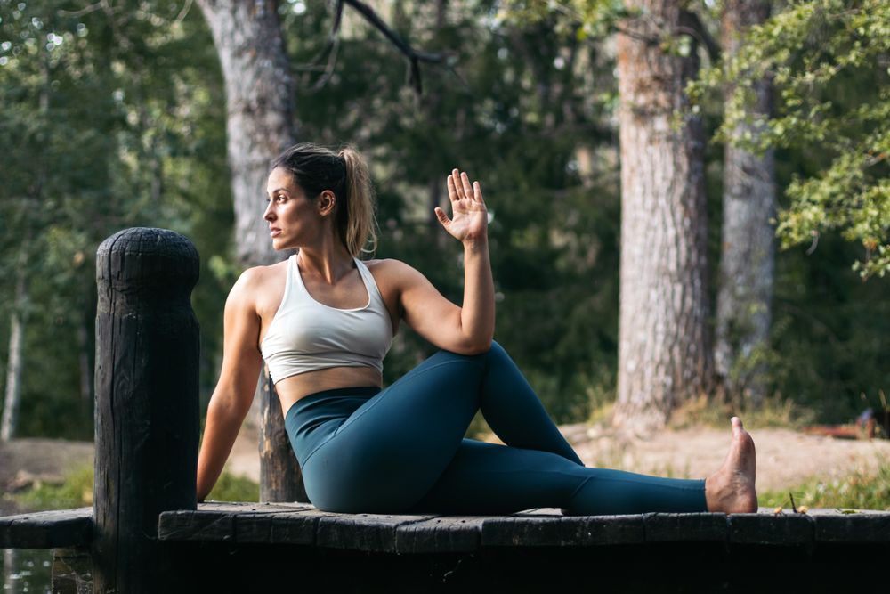 Woman in sportswear doing yoga in nature near a lake