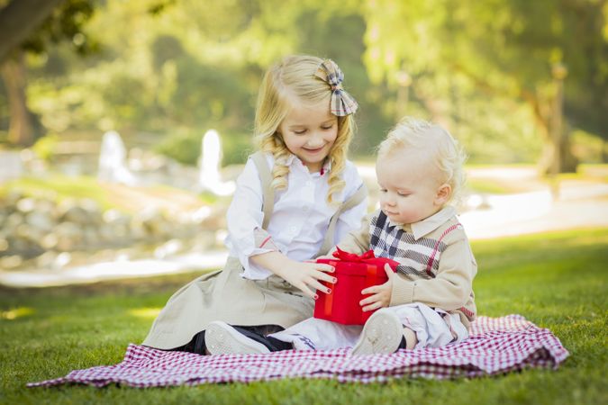 Little Girl Gives Her Baby Brother A Gift at Park.