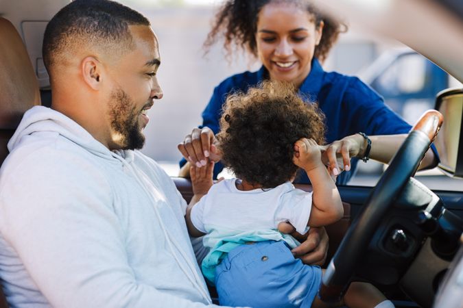 Little boy sitting on father's hips with his mother out the window