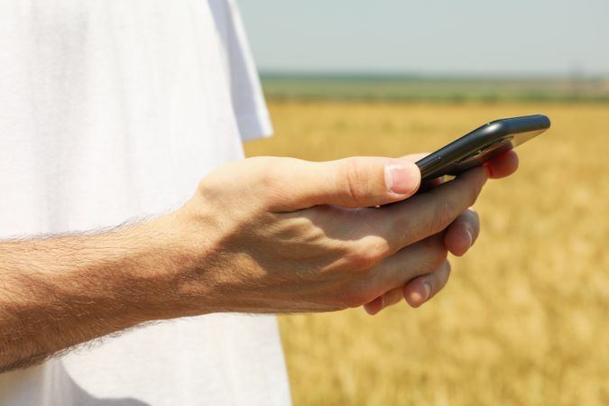 Man with phone in barley field. Agriculture business
