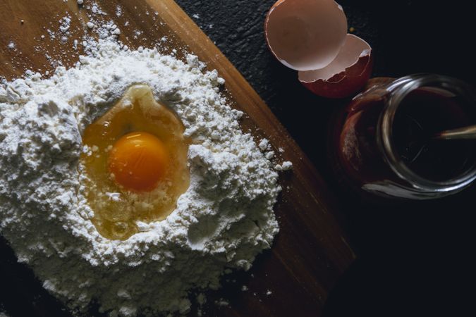 Broken egg and flour on black background