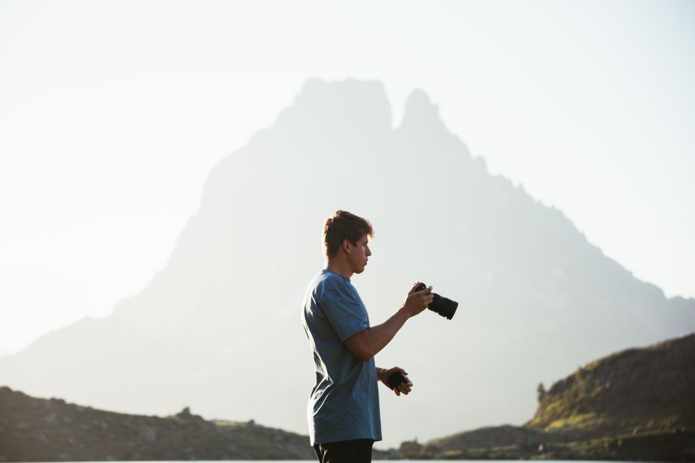 Unrecognizable man taking photo of mountain landscape