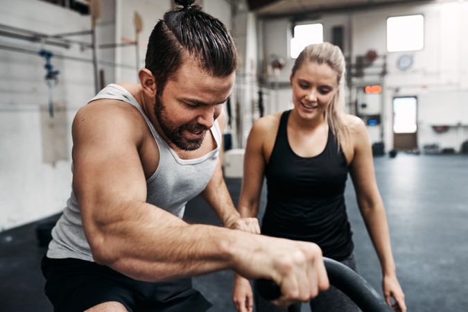 Man riding exercise bike while woman looks on