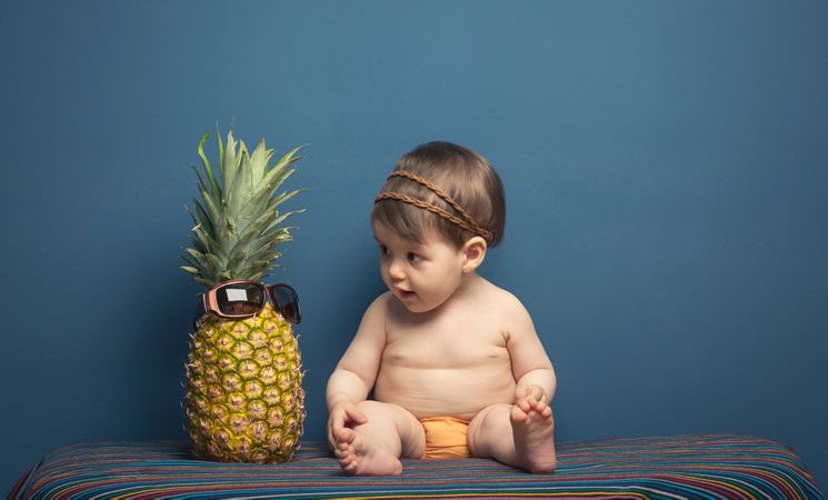 Happy baby playing with a pineapple